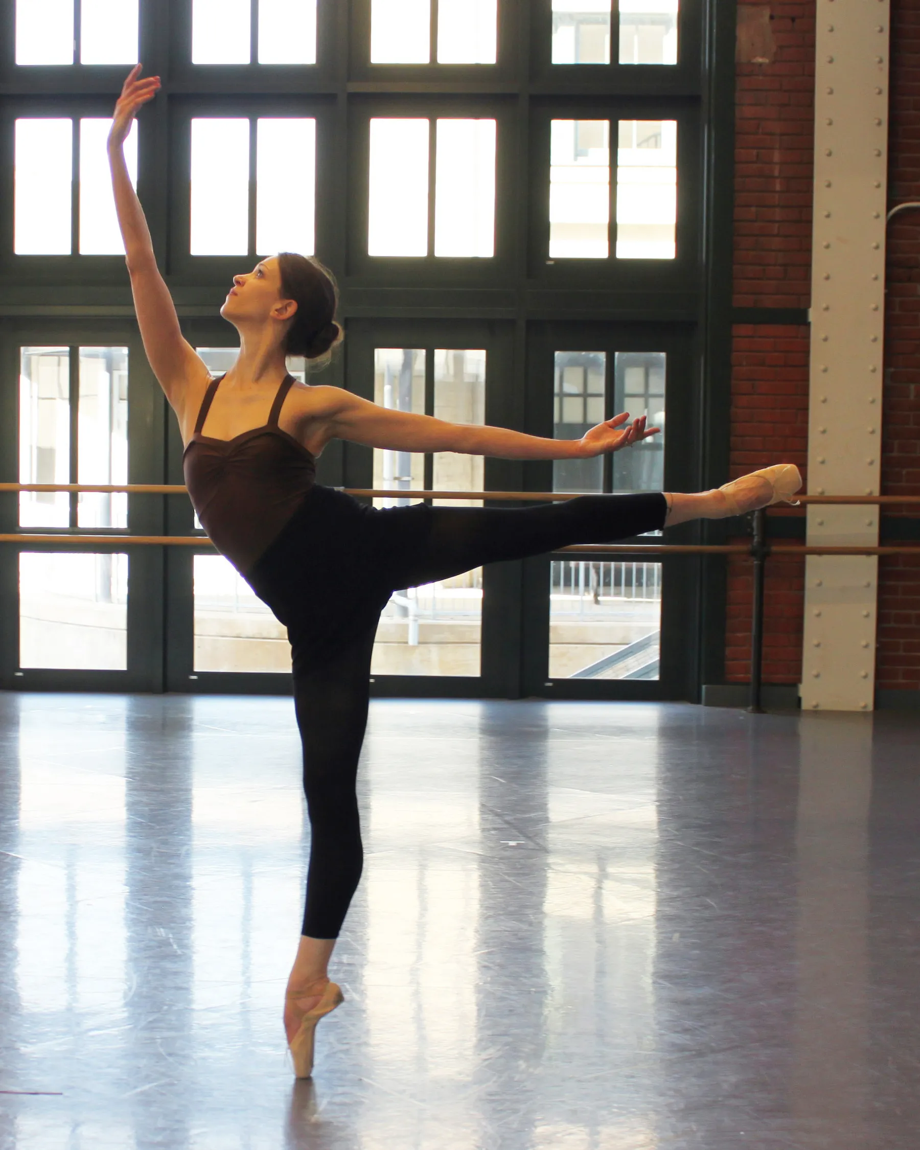 Malena Ríos en arabesque sobre puntas, estudio con barra y ventanales